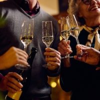 Close up of people toasting champagne while celebrating Christmas at home.